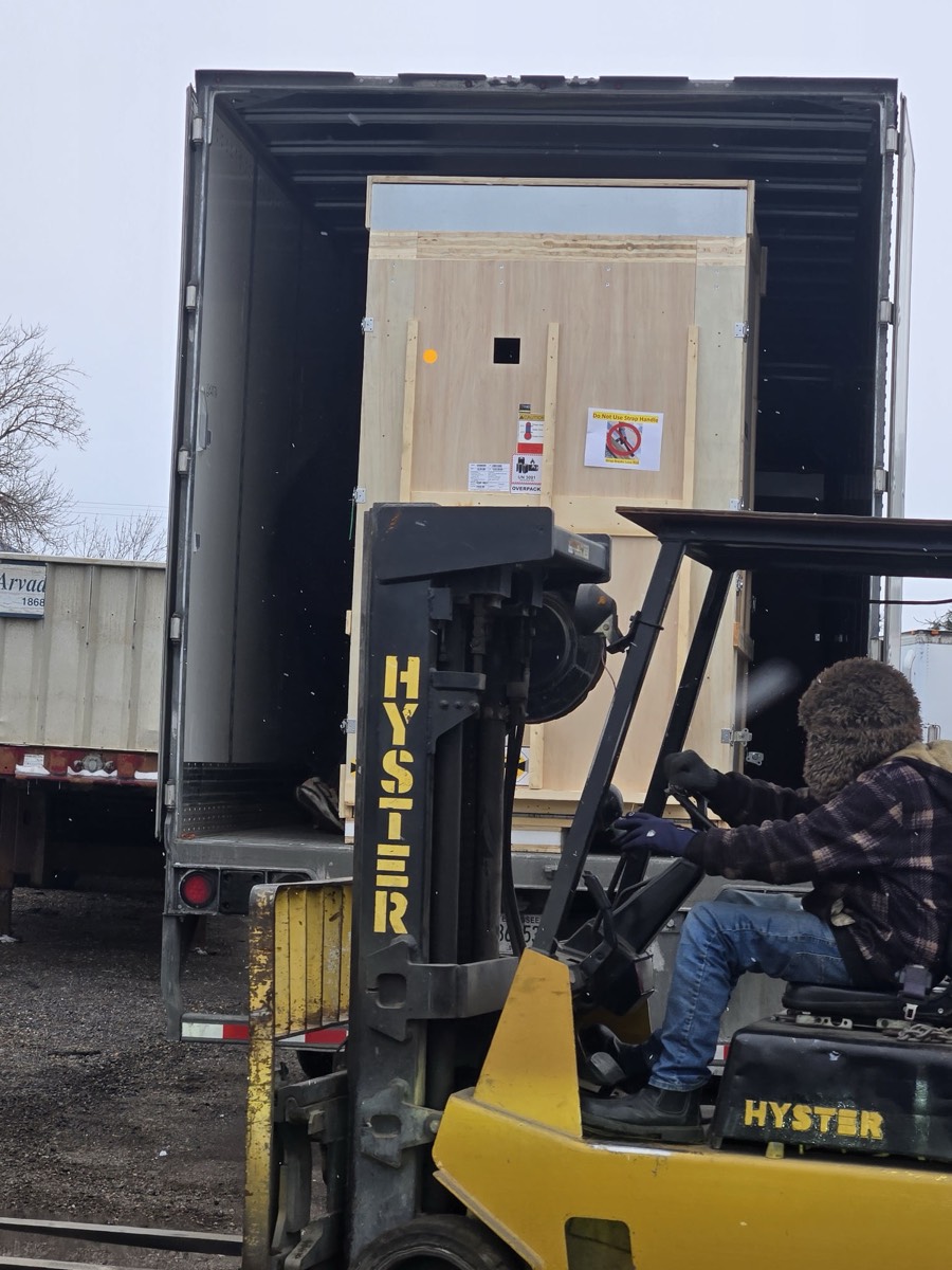 Forklift operator removing shipping crate from semi-trailer in Denver